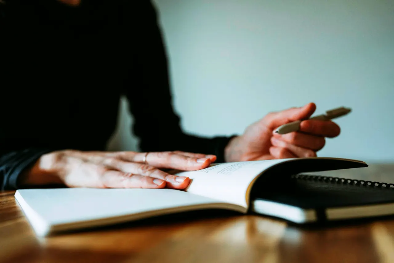 Een hand met pen boven een open schrift