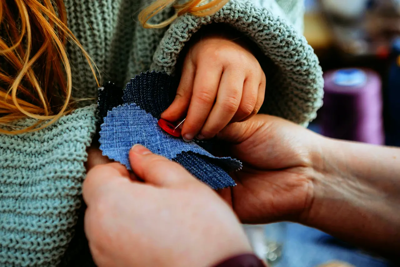 An adult and a child holding pieces of fabric together